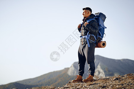 在山顶站立的徒步旅行设备中的男性背包男冒险登山者耐力地平线活动背包天空自由岩石爬坡图片