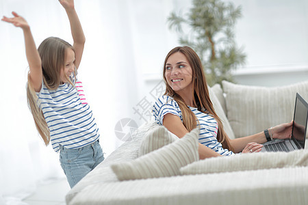 母亲和女儿坐在客厅沙发上的睡椅上幸福女孩孩子房间友谊成人童年快乐家庭电脑图片