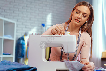 从事纺织厂缝纫机的年轻女裁缝者爱好职场衣服女裁缝工厂商业机器接缝织物材料作坊高清图片素材