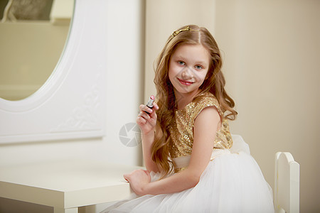 一个小女孩靠近镜子 画着唇唇膏眼睛乐趣喜悦裙子女儿化妆品快乐女士微笑头发图片