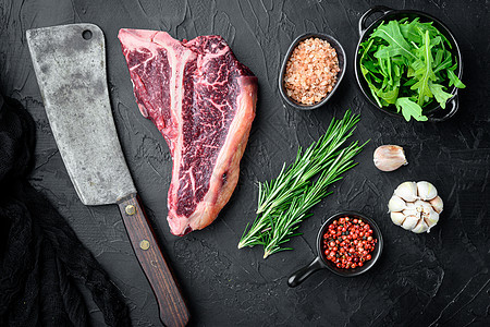 烤肉背景 生牛肉T骨牛排 配有香料和药草用于烧烤 黑色石块背景 顶楼图片