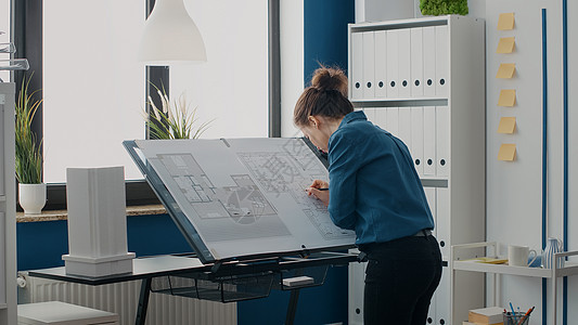 近距离接近女建筑设计师 在设计建筑物布局的蓝图计划上作笔记图片