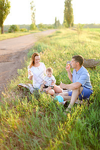快乐的父母坐在草地上 带着小孩和吹泡泡图片