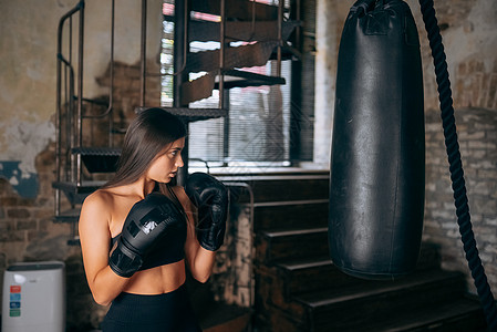 在体育馆打拳击的年轻女子肌肉拳击手绷带冲孔运动员力量培训师锻炼运动训练图片