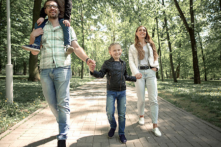 与子女一起在城市公园沿路行走的家庭快乐父亲女孩蓝图父母男生儿子享受公园小路图片