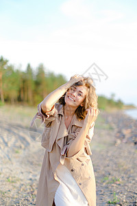 身着大衣和白礼服的年轻天主教女孩站在沙滩上 背景有树木图片