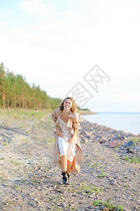 站在海边的年轻女士带着树在背景中微笑图片