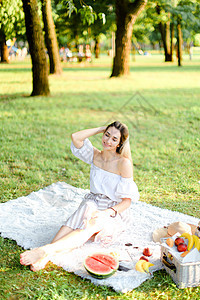女孩坐在公园里满是水果的笼子上图片