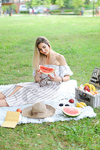 女孩坐在水果和帽子旁边的格子上 吃西瓜 本底草图片