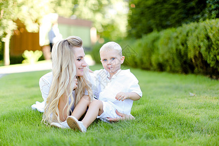 年轻的金发母亲坐在院子里的草地上 带着小宝宝坐着图片