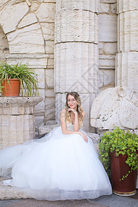 白种人美丽的新娘坐在古代柱子旁边 穿着白色的礼服图片