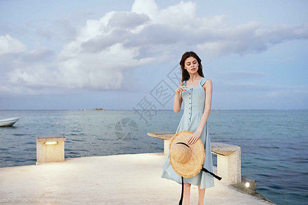 妇女在海滨附近穿着衣服 夏季休闲生活方式平衡乐趣喜悦休息海洋假期帽子女性日落游客图片
