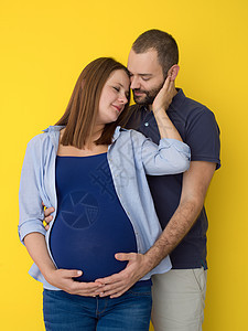 在黄色背景下被孤立的怀孕夫妇男人父亲丈夫男性婴儿幸福夫妻工作室母亲成人图片