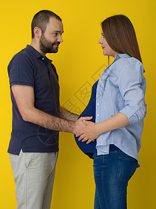 在黄色背景下被孤立的怀孕夫妇母性婴儿男性母亲家庭妻子腹部女性父亲幸福图片