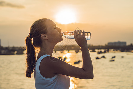 阳光明日 运动妇女户外饮用水闲暇享受锻炼食物太阳海滩女孩训练日落天际图片