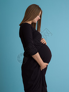 蓝色背景对孕妇的纵向照像工作室婴儿母亲微笑肚子身体女士快乐女性怀孕图片