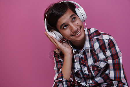 阿拉伯穿戴耳机和听音乐的少年男孩乐趣电话快乐微笑紫色青年男人男生技术享受图片