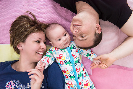 笑笑的年轻夫妇与婴儿躺在一起的最佳景象说谎地面男生父亲毯子童年妻子母亲男人女士图片