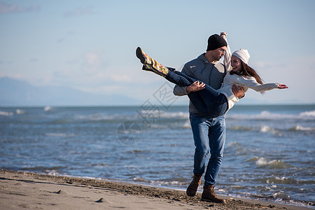 秋天阳光明媚的一天 在海滩上爱一对年轻夫妇手机记忆乐趣拥抱营火夫妻晴天女士男人休息图片