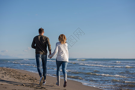 秋天阳光明媚的一天 在海滩上爱一对年轻夫妇假期男性夫妻记忆拥抱男人休息营火手机棉花图片