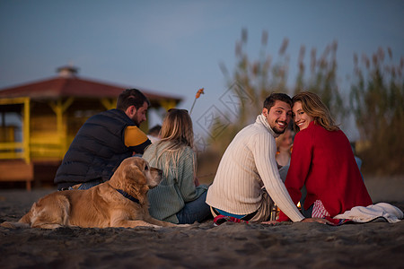 在海滩日落时和朋友共度欢乐的情侣衣服假期啤酒休闲火焰男人活动潮人女性快乐图片
