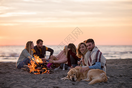 在海滩日落时和朋友共度欢乐的情侣动作友谊火焰假期休闲男人朋友们快乐篝火营火图片
