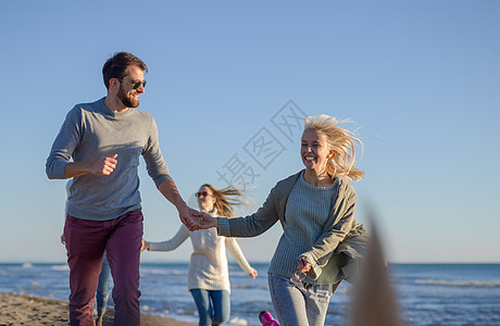 秋天在海滩上奔跑的一群朋友友谊服装情侣幸福帽子女性年轻人鹅卵石跑步朋友们图片