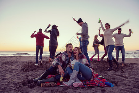 在海滩日落时和朋友共度欢乐的情侣潮人啤酒乐趣朋友们休闲篝火幸福友谊营火沙滩图片