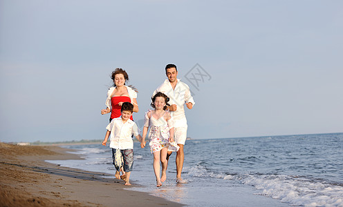 快乐的年轻家庭在海滩上玩得开心儿子活动乐趣喜悦孩子跑步闲暇女孩成人父母图片
