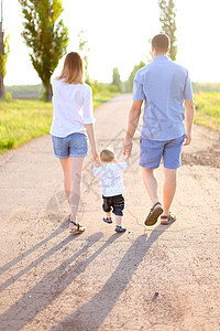 年轻妈妈和父亲带着小宝宝在路上行走 阳光灿烂的天气闲暇母亲幸福阳光孩子阴影休息树木儿子晴天图片