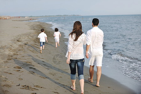 快乐的年轻家庭在海滩上玩得开心男人女性活动假期跑步孩子爸爸后代闲暇儿子图片