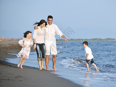快乐的年轻家庭 在日落时在海滩上玩得开心天空孩子旅行成人女儿父亲海洋父母母亲女孩图片