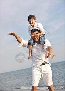 快乐的父亲和儿子玩得开心 在海滩上享受时光孩子拥抱喜悦海洋男人成人天空时尚男性幸福图片