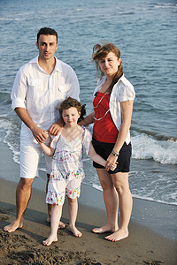 快乐的年轻家庭在海滩上玩得开心喜悦儿子微笑父母母亲童年闲暇男人海洋天空图片
