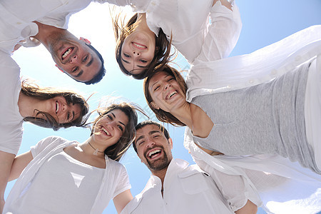 一群快乐的年轻人在沙滩上围成一圈微笑青年成人海滩天空团队喜悦幸福乐趣团体图片