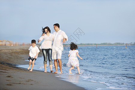 快乐的年轻家庭 在日落时在海滩上玩得开心男性儿子太阳女儿微笑女孩天空旅行热带母亲图片