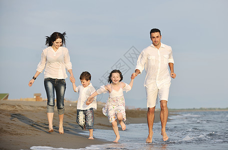 快乐的年轻家庭 在日落时在海滩上玩得开心喜悦童年父母孩子们海洋天空爸爸女儿假期生活图片