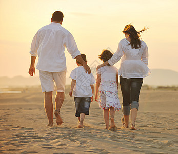 快乐的年轻家庭 在日落时在海滩上玩得开心父母微笑童年儿子男性爸爸太阳女性孩子们海洋图片