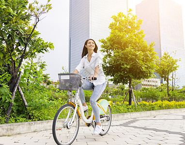 年轻有吸引力的女子骑自行车穿过城市公园进入城市公园女孩乐趣运输公园女性女士旅行运动建筑骑术图片