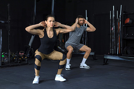 穿运动服在健身房做蹲下锻炼的合身夫妇肌肉夫妻运动专注运动装运动员哑铃动机男人活动图片