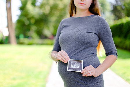 身着灰色衣服的年轻孕妇留有超声波照片图片