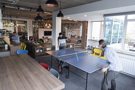 在有创意的办公空间打乒乓网球竞赛办公室女士男人同事商务人士运动桌子比赛图片