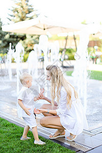年幼的母亲在喷泉附近和小孩玩耍图片