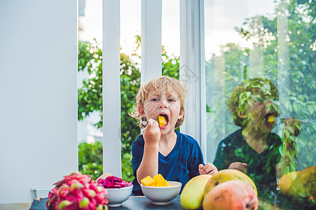 小可爱男孩在阳台上吃芒果甜点饮食食物乐趣蓝色热带婴儿孩子情调水果图片