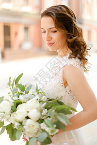 幸福的新娘拿着一束鲜花 穿着白色礼服图片
