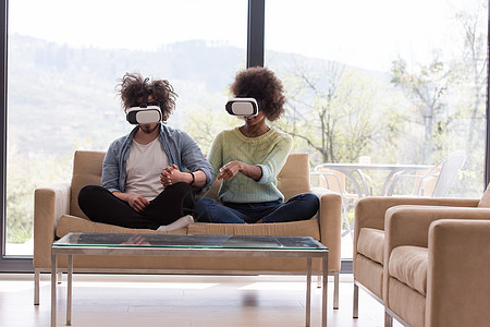 使用虚拟现实耳机的多种族夫妇女士沙发技术乐趣享受虚拟现实耳机创新男人视频图片