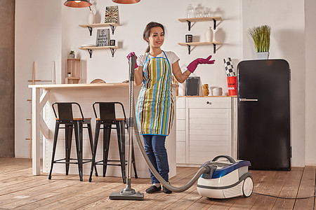 年轻妇女在家中厨房用吸尘器清洁工做清洁和杂务 内地细心整洁职责中段电气地面客厅清洁度微笑身体电子产品家具背景图片