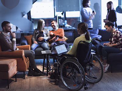 坐在轮椅上的年轻妇女在办公室用笔记本电脑工作 接受家庭教育的概念成人微笑工人技术药品残障程序员团队员工同事图片