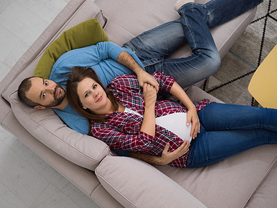 怀孕夫妇在沙发上放松微笑母亲丈夫成人腹部女性家庭孩子幸福房间图片