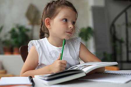 小女孩坐在家里的书桌上做作业 自学材料 看书 远程教育的概念孩子女孩技术药片互联网阅读童年女性学生教育图片